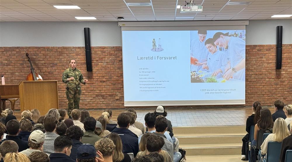 En representant fra Forsvaret på scenen i aula på videregående skole - Klikk for stort bilde