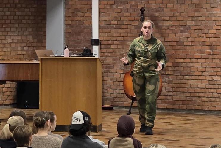 Representant fra forsvaret står foran skoleklasse i aula - Klikk for stort bilde